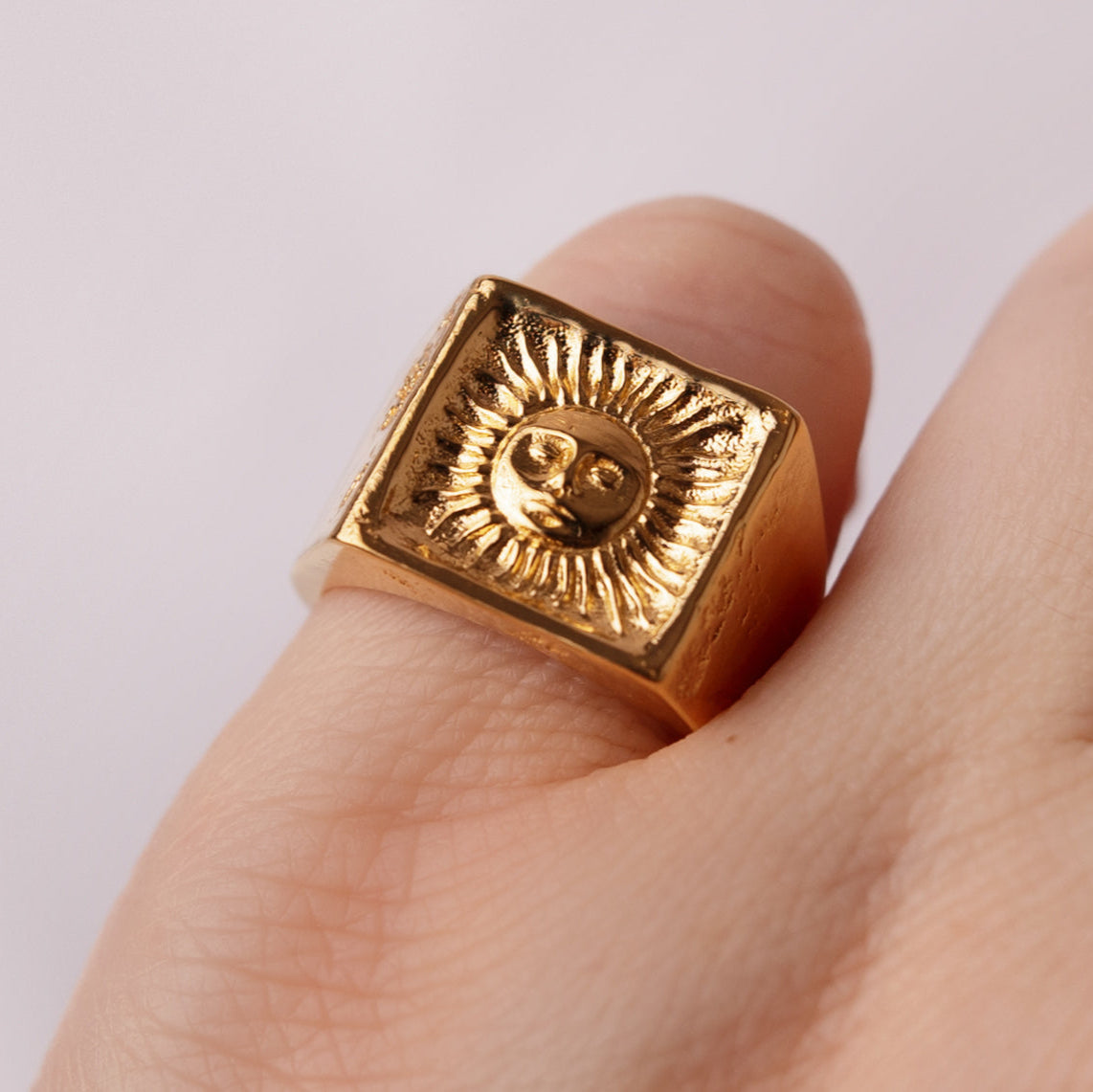 sun face gold ring on finger